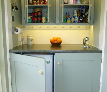 Kitchen storage using bespoke lower cupboard doors to conceal appliances and upper cupboard for food